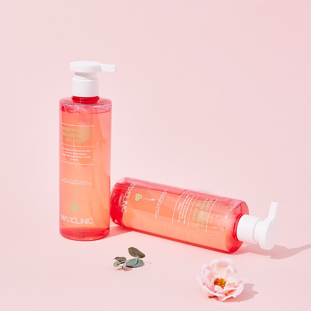 Two pink Maxclinic Oil Foam bottles on a pink background with a flower